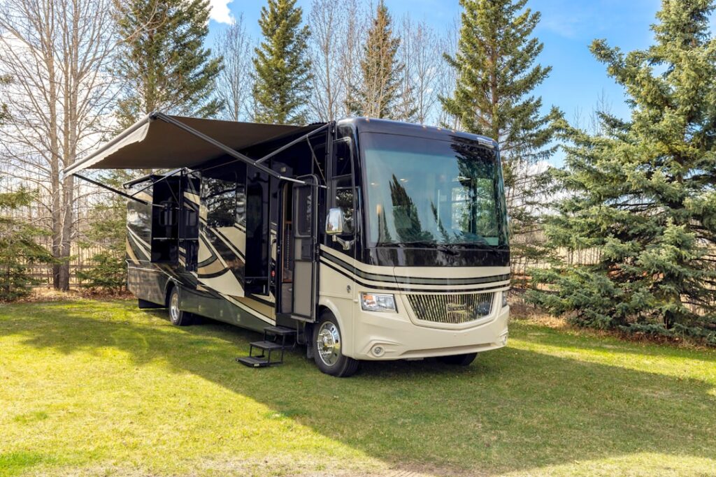 a motor home parked in the grass near some trees