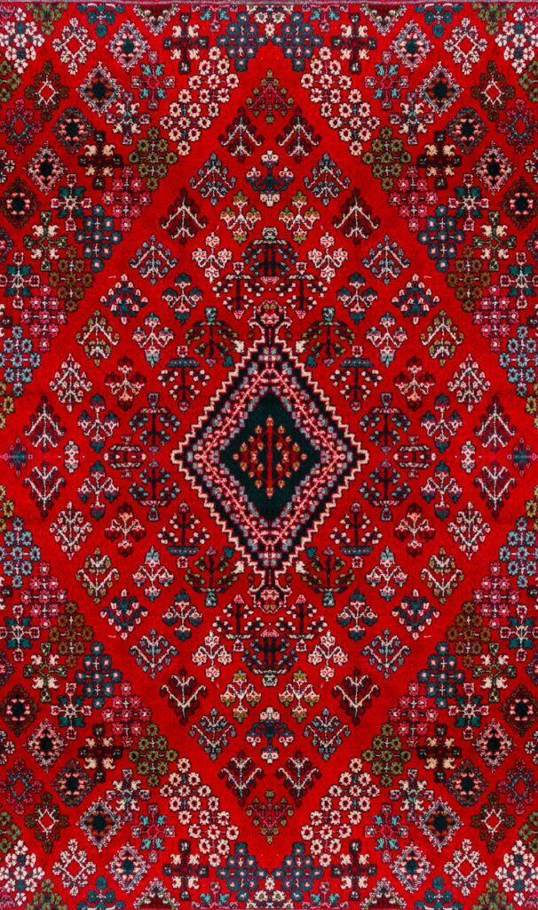 A red Persian rug with intricate geometric patterns and a central diamond motif