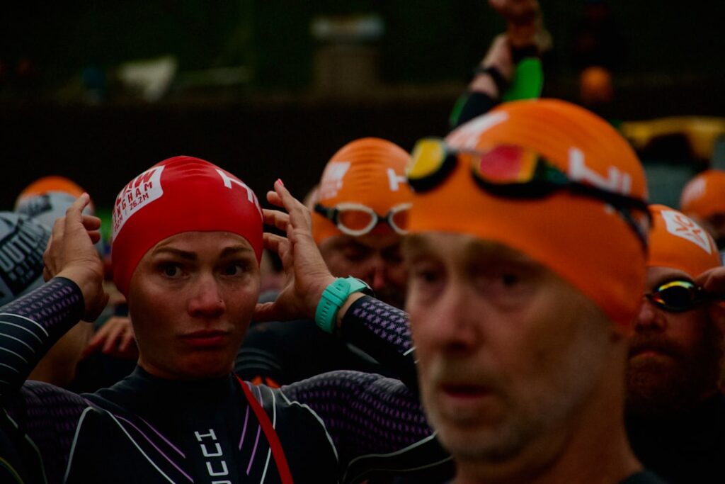 Swimmers in orange and red caps preparing for race