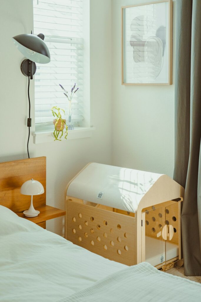 Wooden baby crib next to a bed in a room.